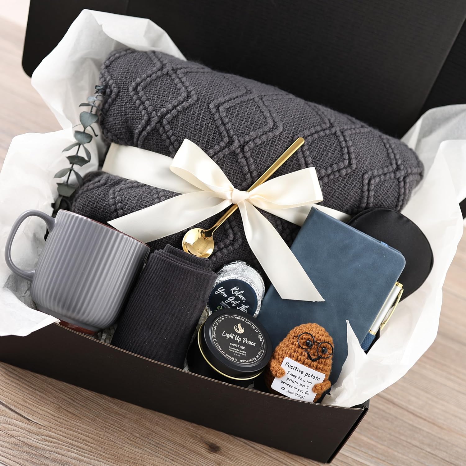 castateo-thoughtful-comfort-care-package-grey-12-piece-gift-box-for-adults-01 A grey and navy CASTATEO comfort care package featuring a knitted throw blanket, ceramic mug, and a small 'Positive Potato' t