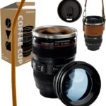 Black camera lens coffee mug with a cup sleeve and silicone straw, showcasing its unique design and accessories.