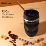 Black camera lens coffee mug with a cup sleeve and silicone straw, showcasing its unique design and accessories.