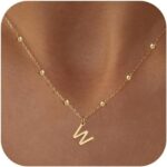 Close-up of a delicate 14K gold-plated initial 'W' necklace on a simple bead chain, worn by a woman.