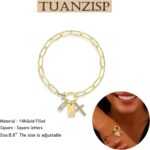 Close-up of a gold-plated paperclip link chain bracelet with a letter J initial charm and a small cross charm, on a light bac